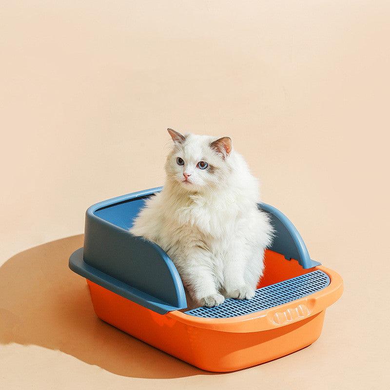 Cat sitting inside an orange and gray litter box on a beige background
