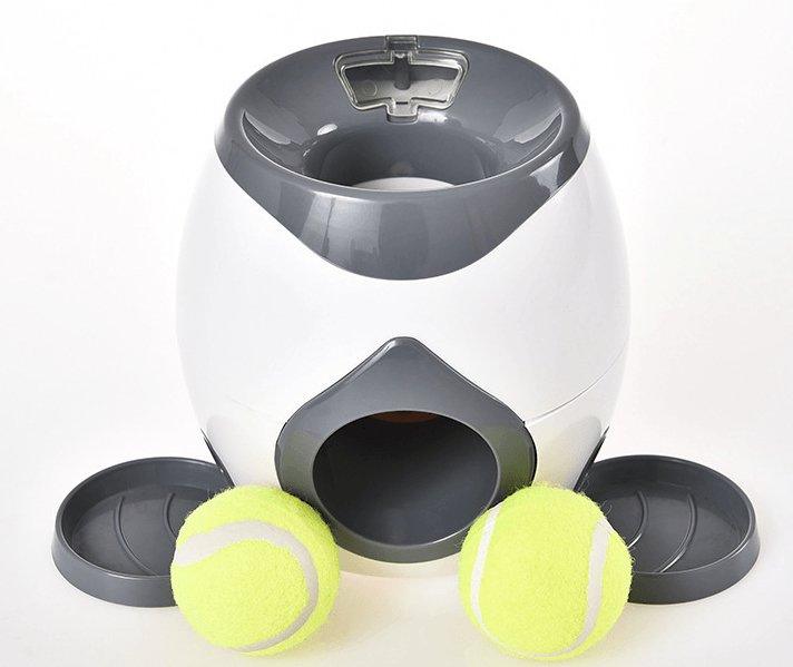 White and gray ball launcher with two yellow tennis balls on a white background