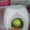 White electronic device with a green ball inside, on a pink surface with a Deli brand appliance in the background.