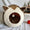 Cat-shaped pet bed with a small ball inside, placed on a white surface with a plant and paper in the background.