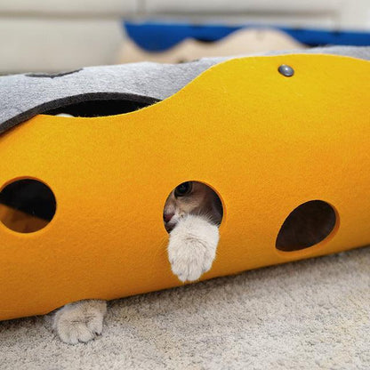 Cat peeking out from a yellow cat play structure with multiple holes.