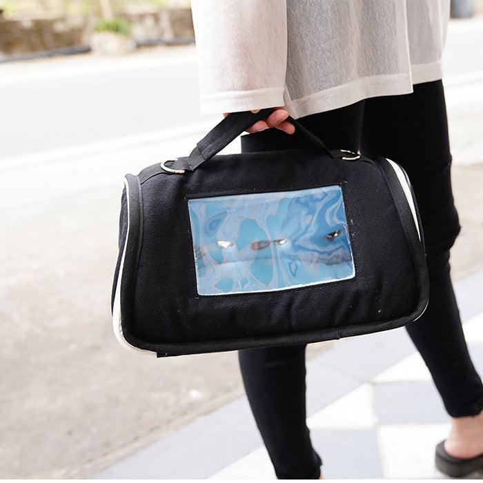 Person holding a black pet carrier with a blue butterfly design on a blurred background