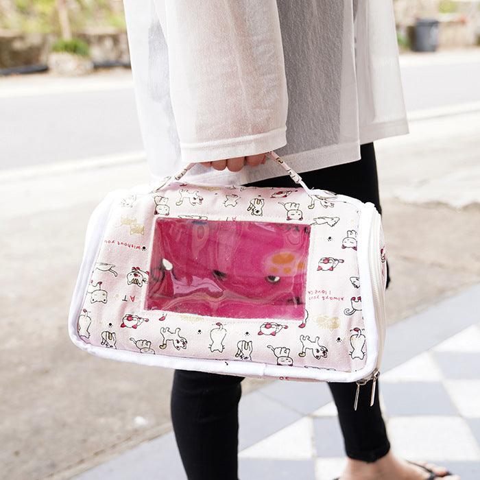 Person holding a pink pet carrier with cartoon designs outdoors.