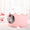 Cat peeking out from a pink pet house with a snowman toy in the background