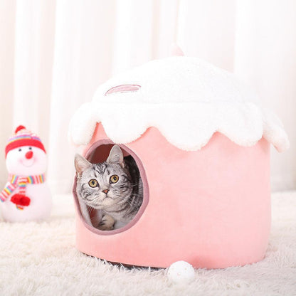 Cat peeking out from a pink pet house with a snowman toy in the background