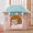Cat peeking out from a pink pet house with a teal roof