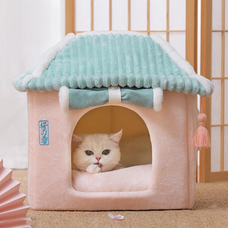 Cat peeking out from a pink pet house with a teal roof