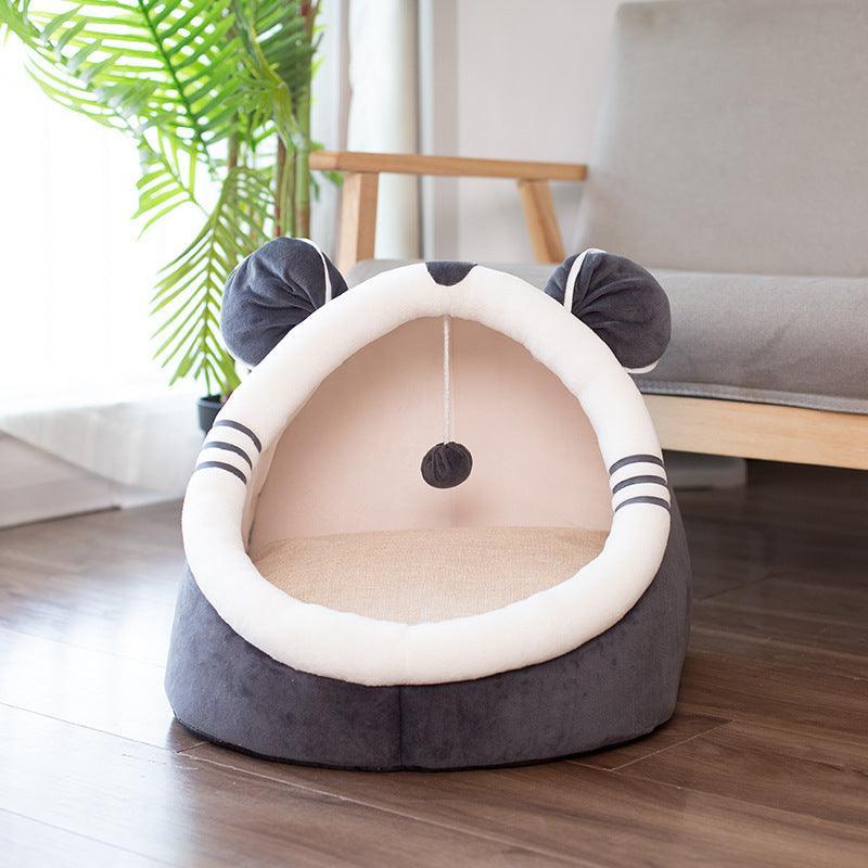 Cat-shaped pet bed on a wooden floor with a plant in the background