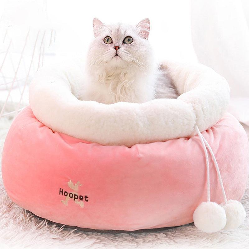 White cat sitting on a pink pet bed with 'Hoopet' branding.