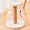 Cat tree with sisal-covered post, white cushion, and hanging toys on a wooden surface.