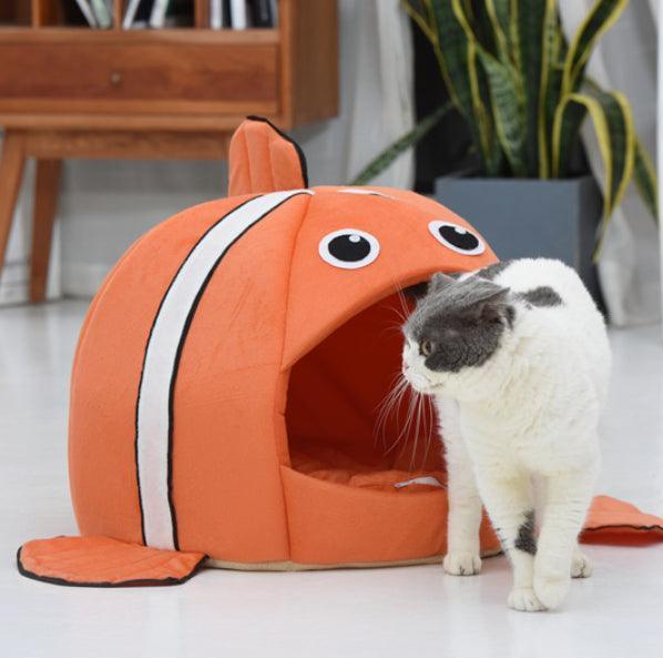 Cat standing next to a fish-shaped pet bed in a home setting