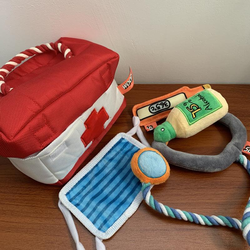 First aid kit, plush toys, and a bottle-shaped toy on a wooden surface.