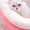 White cat lying on a pink cushion with a soft focus background