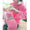 Person wearing a pink hoodie with leopard print text, holding a small dog in a matching hoodie.