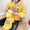 Person wearing a yellow hoodie with text, sitting on a carpeted floor.