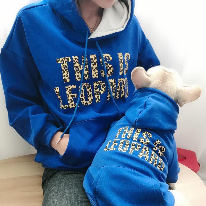 Person wearing a blue hoodie with leopard print text, sitting on a wooden floor.
