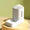 White and gray electronic device on a gold stand with a green background
