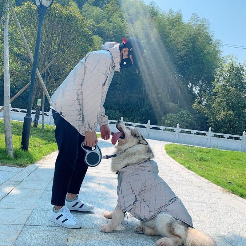 Person and dog wearing matching coats in a park setting