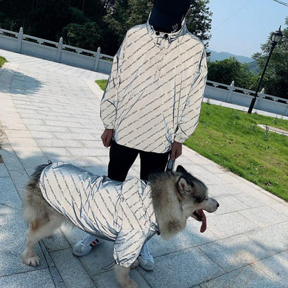 Person and dog wearing matching white hoodies outdoors on a sunny day.